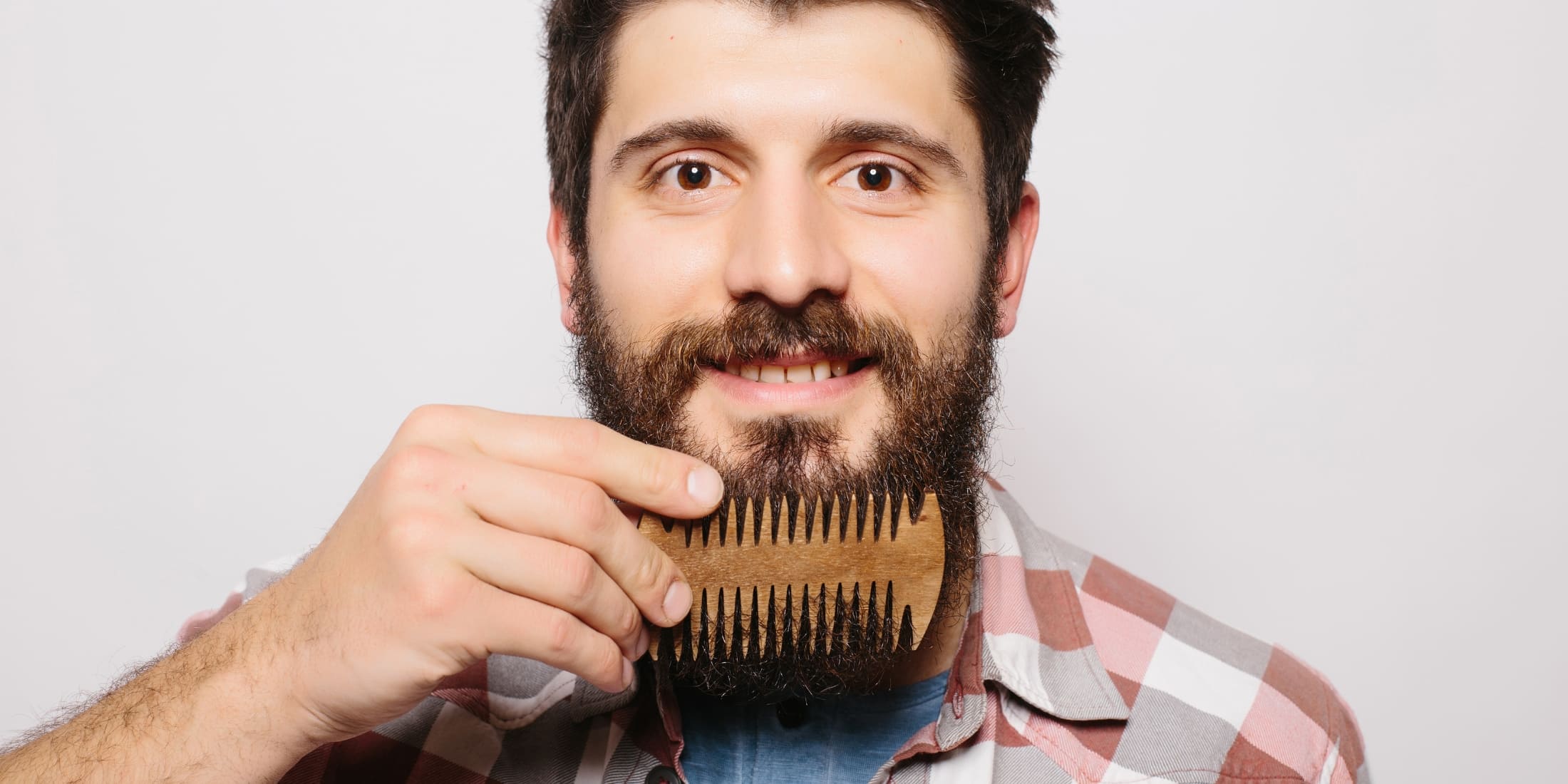 Bearded man combing his beard to avoid common beard grooming mistakes and maintain a neat appearance