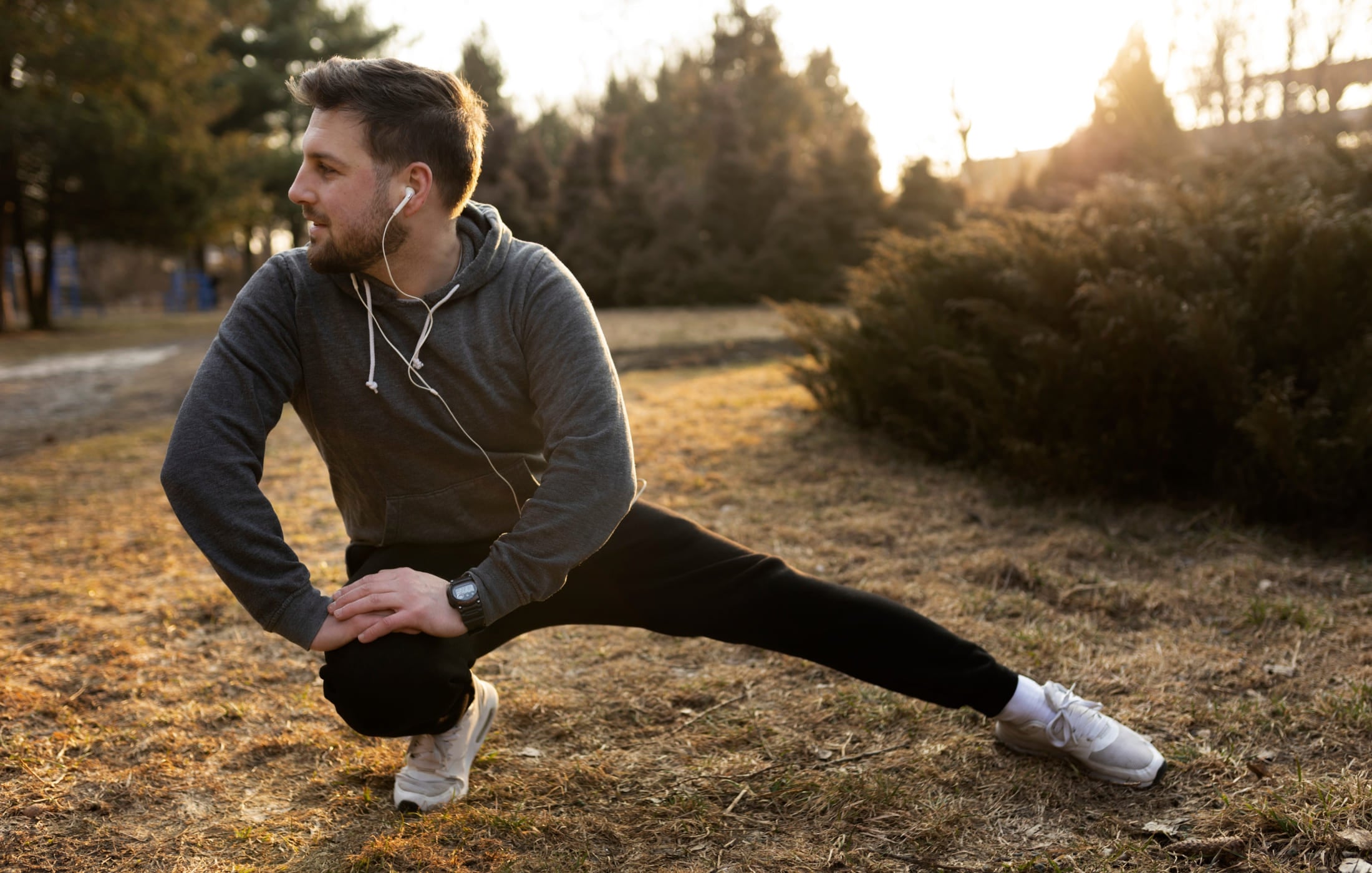 Dad stretching outdoors before jogging, listening to music, and prioritizing physical self-care to stay active and healthy.