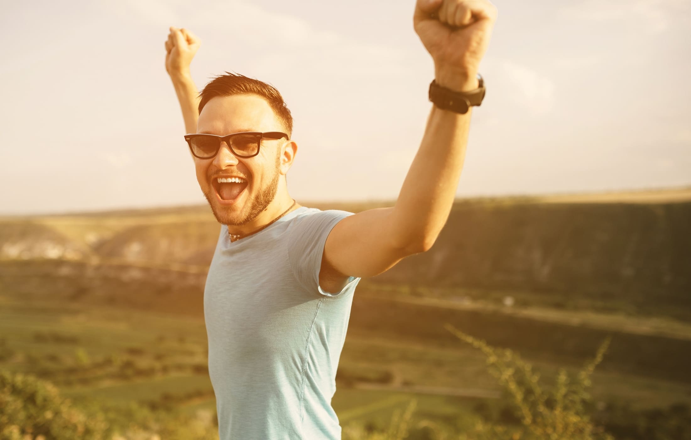 Joyful dad outdoors with arms raised in triumph, celebrating the positive effects of practicing self-care, feeling energized and refreshed.