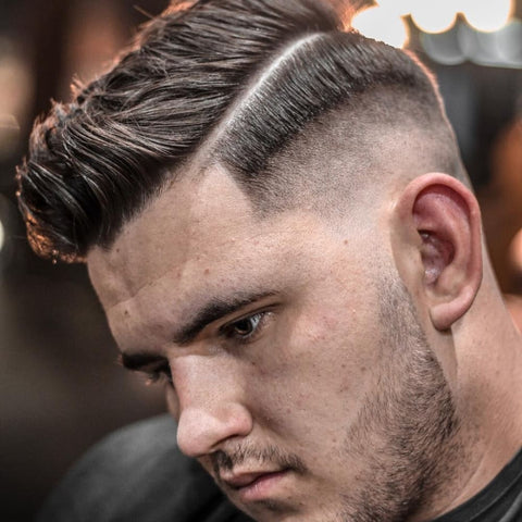 Close-up of a man with a hard part hairstyle, showcasing a sharply defined parting line that contrasts with the clean fade on the sides. This classic men's hairstyle combines precision with a modern edge, offering a bold and refined look that stands out in any setting.