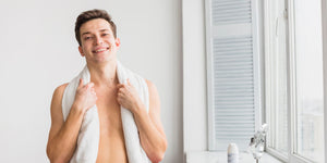 Smiling young man with a towel over his shoulders, ready to start his manscaping below the belt routine