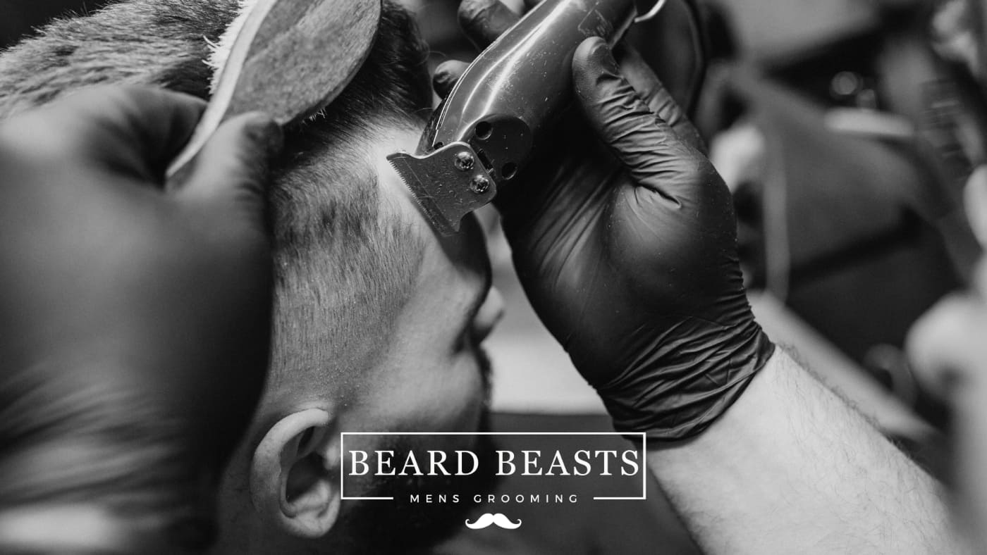 Black and white image of a barber using clippers to give a man a haircut, illustrating meticulous male grooming and the query how often should men get a haircut.