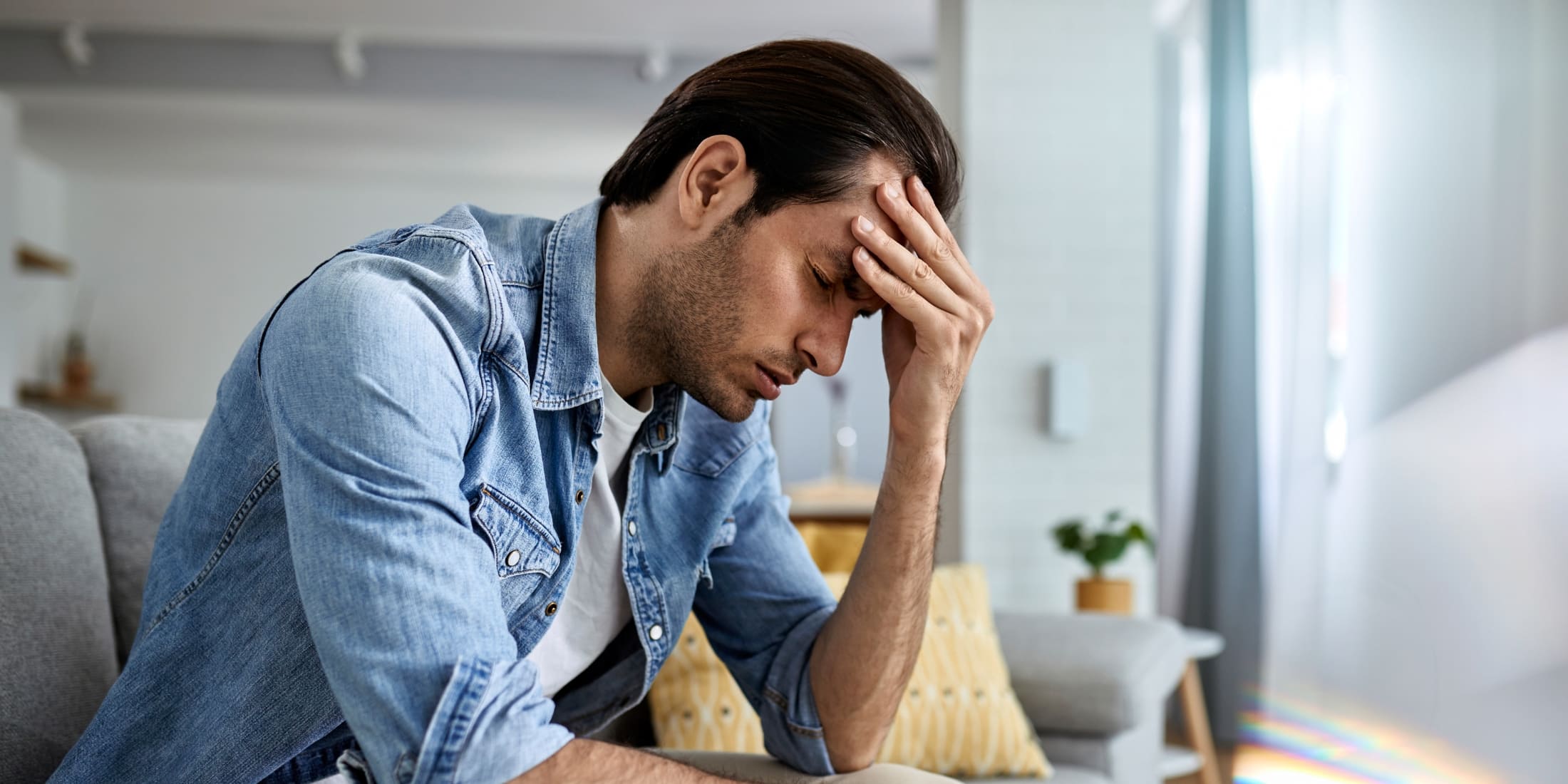 Man holding his head in stress, emphasizing the importance of stress management techniques for men to improve mental health and find effective stress relief.