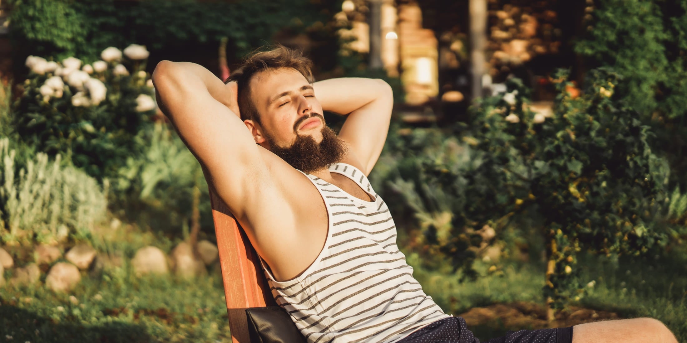 A man relaxing outdoors, reclining with his hands behind his head, basking in the sunlight. This image captures the essence of unwinding and enjoying a peaceful moment, highlighting the importance of rest and relaxation as part of a balanced morning routine for men.