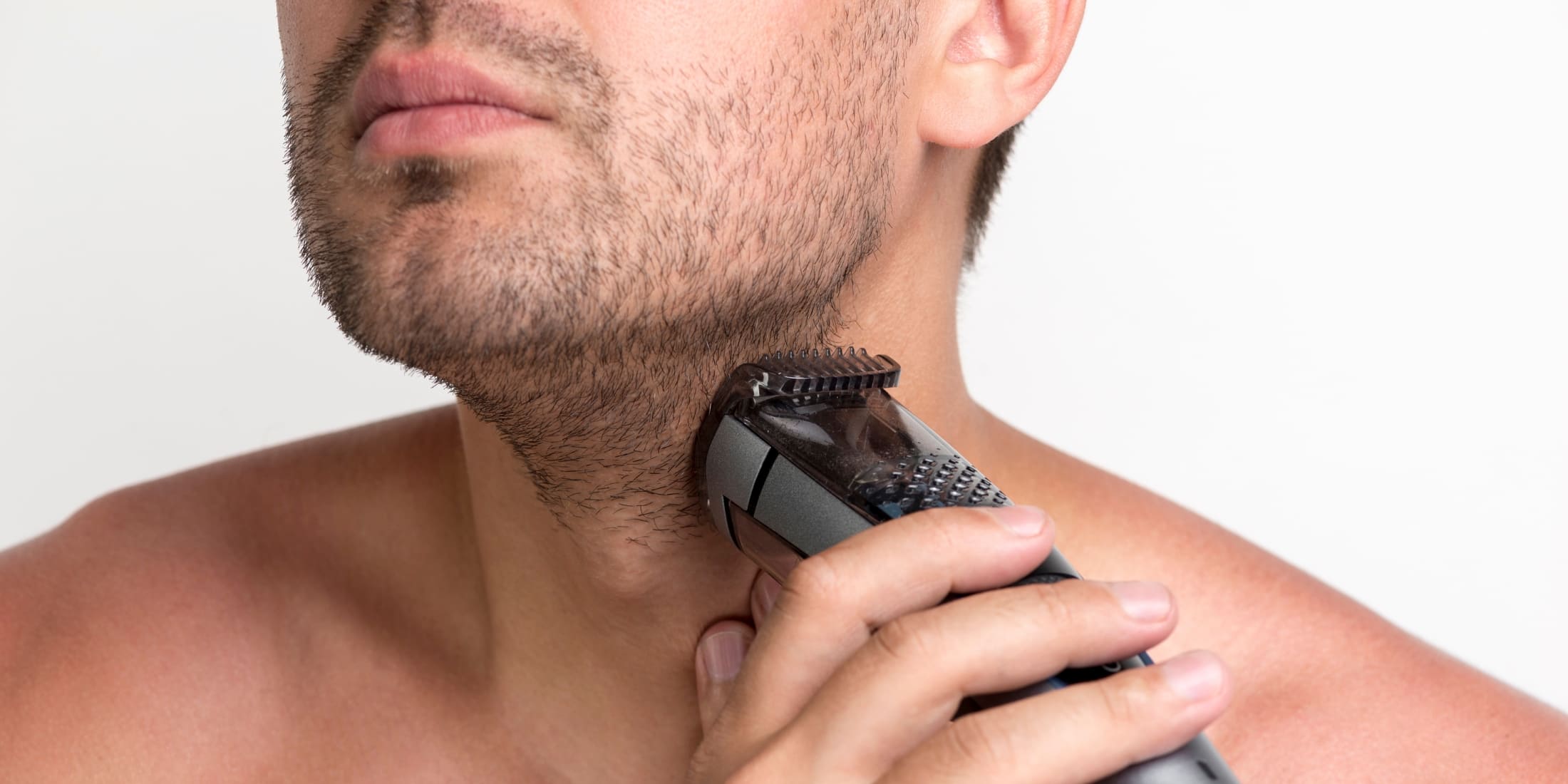 Man using an electric trimmer to groom his stubble, showcasing the precision and ease of maintaining a clean, sharp look. This image is perfect for illustrating beard grooming tips for beginners, emphasizing the importance of regular trimming for a well-maintained beard.