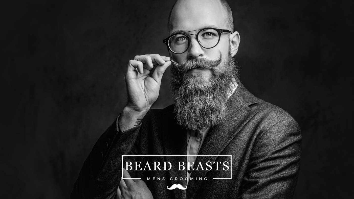 Stylish man demonstrating how to grow a handlebar mustache, representing Beard Beasts Men's Grooming brand.