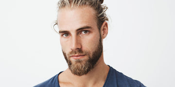 Man with a well-groomed short beard and a man bun, wearing a blue shirt. This image illustrates effective short beard grooming, including tips on maintaining, trimming, and shaping a short beard.