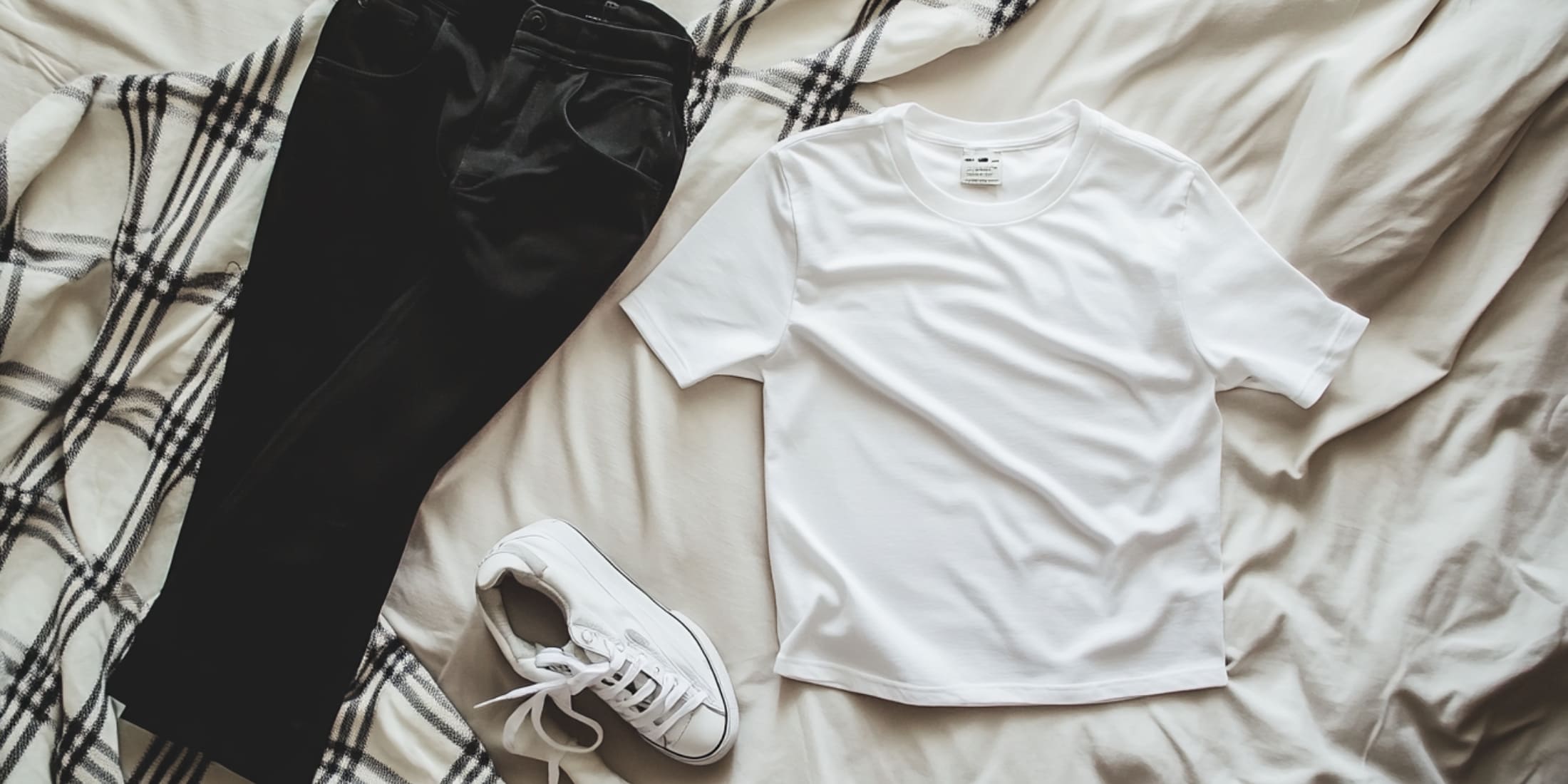 This image shows a neatly organized selection of men's clothing, showcasing a capsule wardrobe—a key concept in men's fashion tips for beginners. The items include folded shirts, sweaters, and jackets in neutral colors like navy, gray, and beige, which are versatile and easy to mix and match. This minimalist collection emphasizes timeless fashion essentials that are perfect for beginners looking to create multiple outfits with fewer pieces. The focus on neutral tones and classic styles makes it easy for anyone starting out in fashion to build a functional, stylish wardrobe.