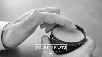 A black and white photo showing a hand delicately scooping out pomade from an open container. The image suggests a comparison or choice between oil-based versus water-based pomade for styling.