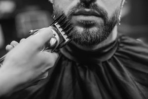 Close-up of a beard being shaped with precision using a beard trimmer equipped with a guard for an even and styled look.