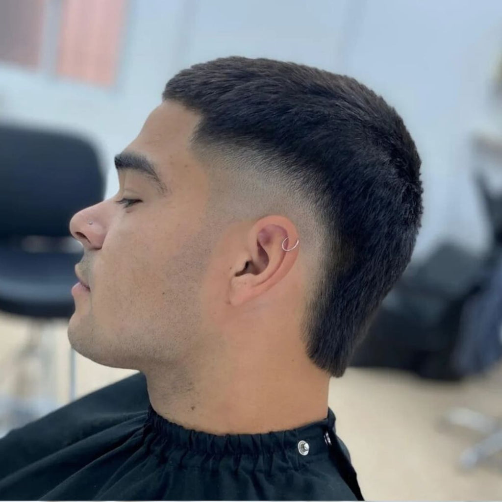 A side profile of a man with a clean, modern haircut featuring a smooth blend around the ear that transitions into short, evenly textured hair on top.