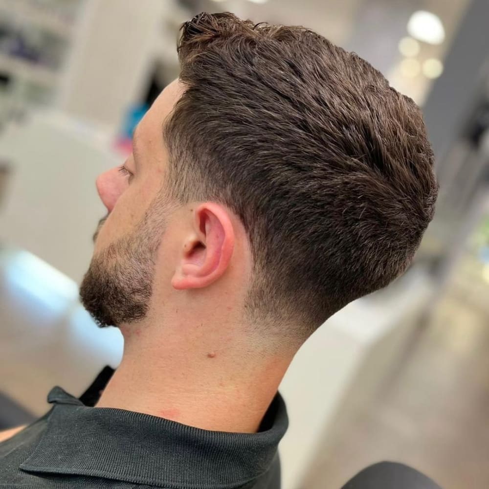 Man with a classic low fade haircut, featuring a smooth transition from longer hair on top to shorter sides and back, highlighting a timeless and versatile look for 2024.