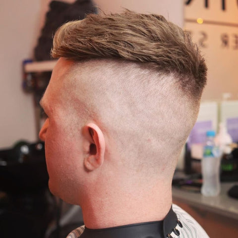 Side view of a man with a Disconnected Undercut, featuring a striking contrast between the long, textured top and the closely shaved sides and back. The sharp disconnect creates a bold, edgy look that stands out, making it a popular choice for those seeking a modern, trendy short hairstyle.