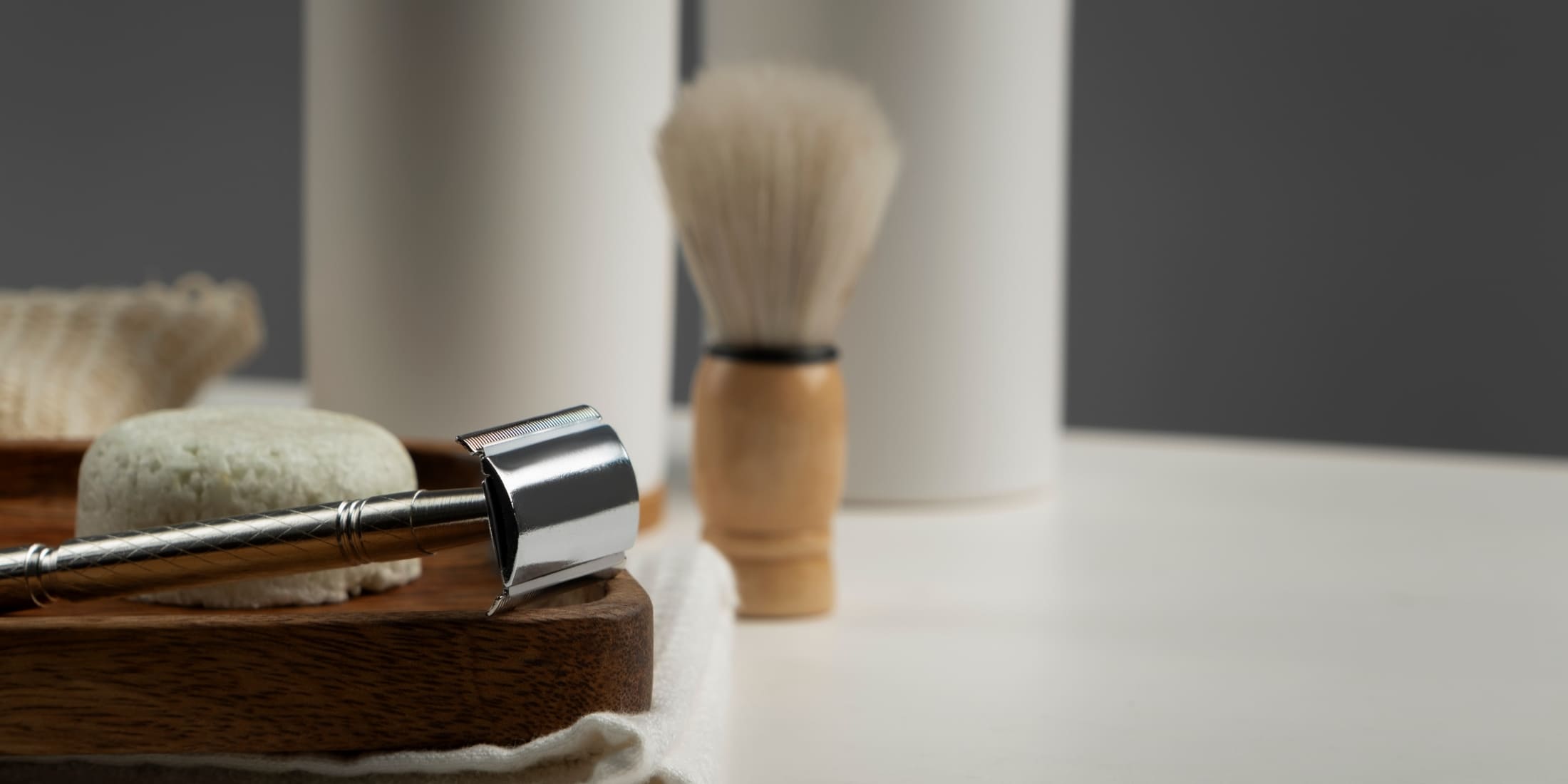 Essential tools for wet shaving, including a safety razor, shaving soap, and a shaving brush, arranged on a wooden tray