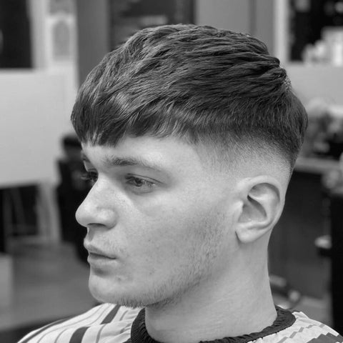 Side profile of a man with a French crop hairstyle, featuring textured hair on top with a short, clean fade on the sides. This classic hairstyle for men is both stylish and low-maintenance, perfect for those seeking a modern yet timeless look that highlights natural texture.