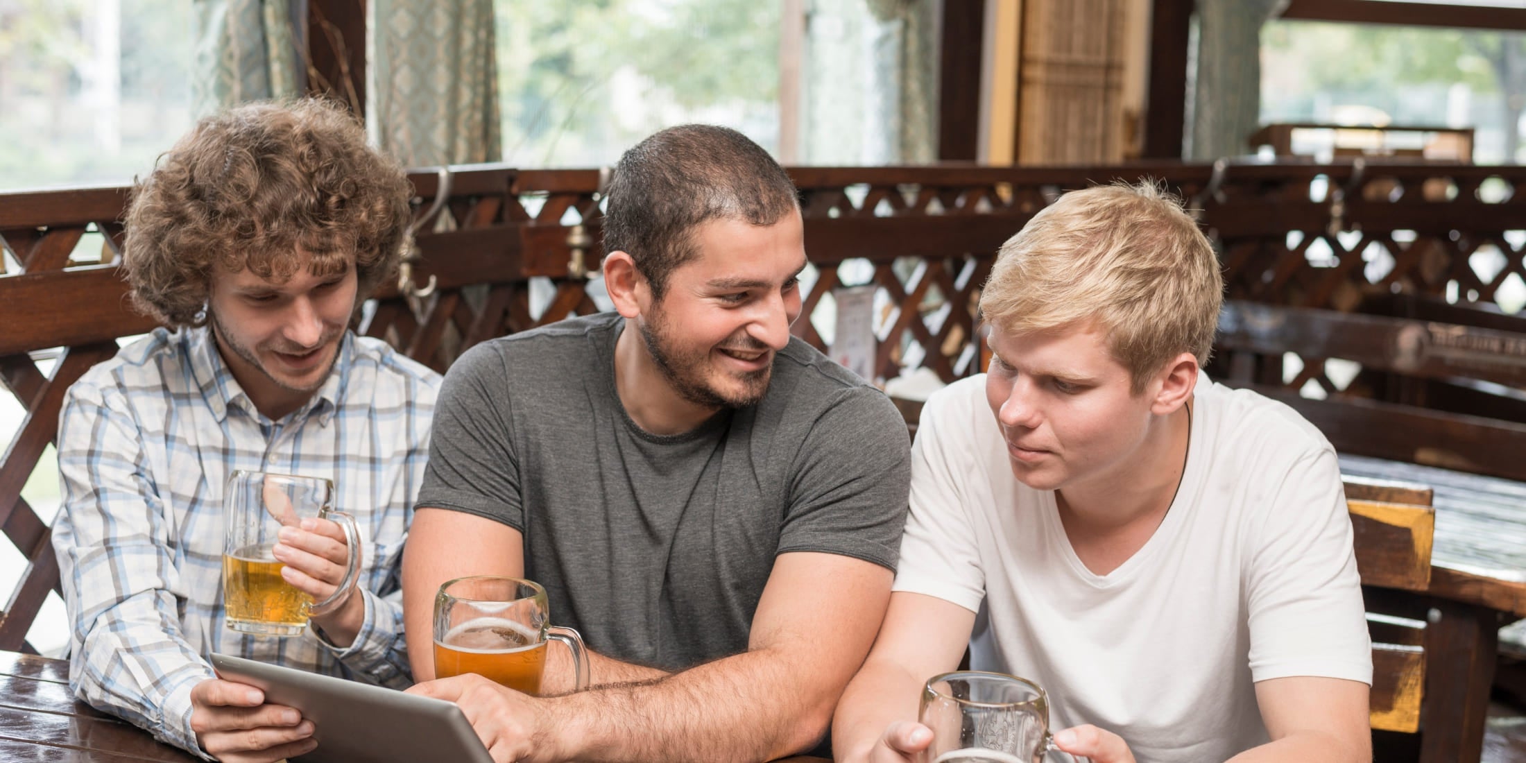 Three friends sit together at a table, enjoying drinks and engaging in conversation, highlighting the importance of social connections. Their smiles and shared moments emphasize the value of friendships and socializing for mental well-being and happiness.