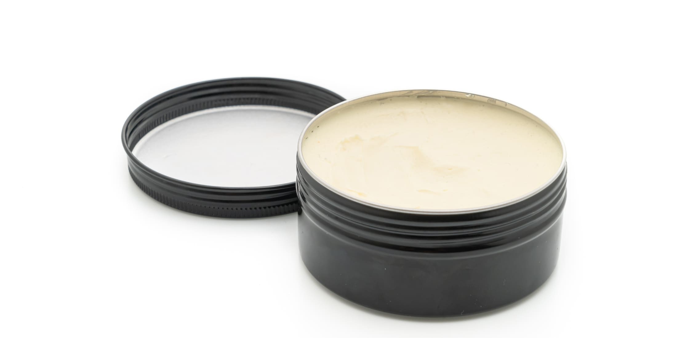 Open container of hair clay showcasing its thick, dense texture, highlighting the key differences in the hair paste vs clay debate for strong hold and matte finish styling.