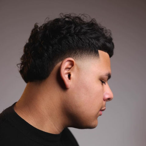 Man with a high taper fade haircut, featuring curly hair on top and smoothly tapered sides. The style showcases a sharp, clean hairline and a well-blended fade for a polished and modern look.