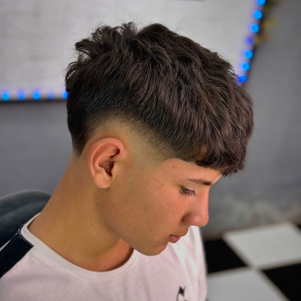 Man with a high taper haircut featuring a mohawk style. The haircut showcases voluminous hair on top with sharply tapered sides, creating a bold and edgy look.