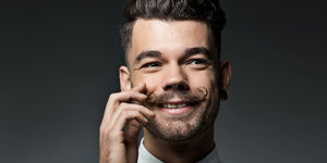 Smiling man with a perfectly styled moustache showcasing the results of using homemade moustache wax 