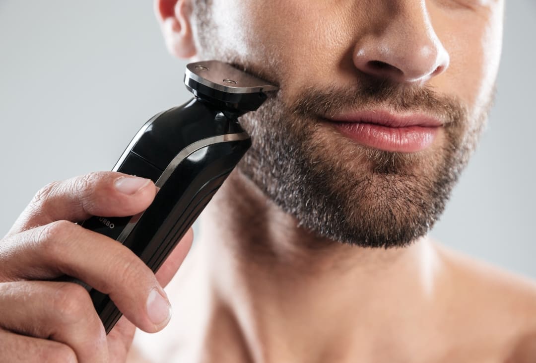 A man attempting to trim his beard after learning how to trim a beard while growing it out