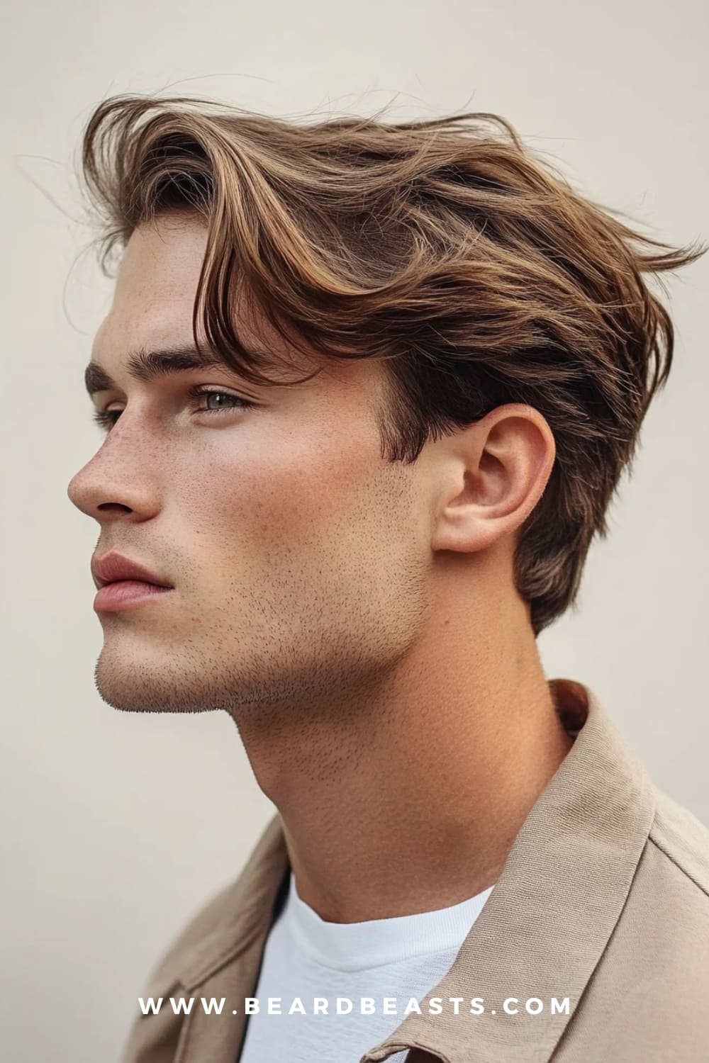 A young man with a stylish layered flow haircut, featuring medium-length brown hair that has been carefully layered to create texture and movement. The hair flows naturally away from his face, with the layers adding volume and a dynamic, windswept look. The side profile highlights the precision of the cut, showcasing the layers that give the hairstyle depth and structure. The man’s light stubble complements his clean, sharp appearance, and he is dressed in a casual beige jacket over a white t-shirt, adding to the overall modern and effortless vibe. This layered flow haircut is a perfect example of men's flow hairstyles trending in 2024, ideal for those looking to add dimension and style to their hair.