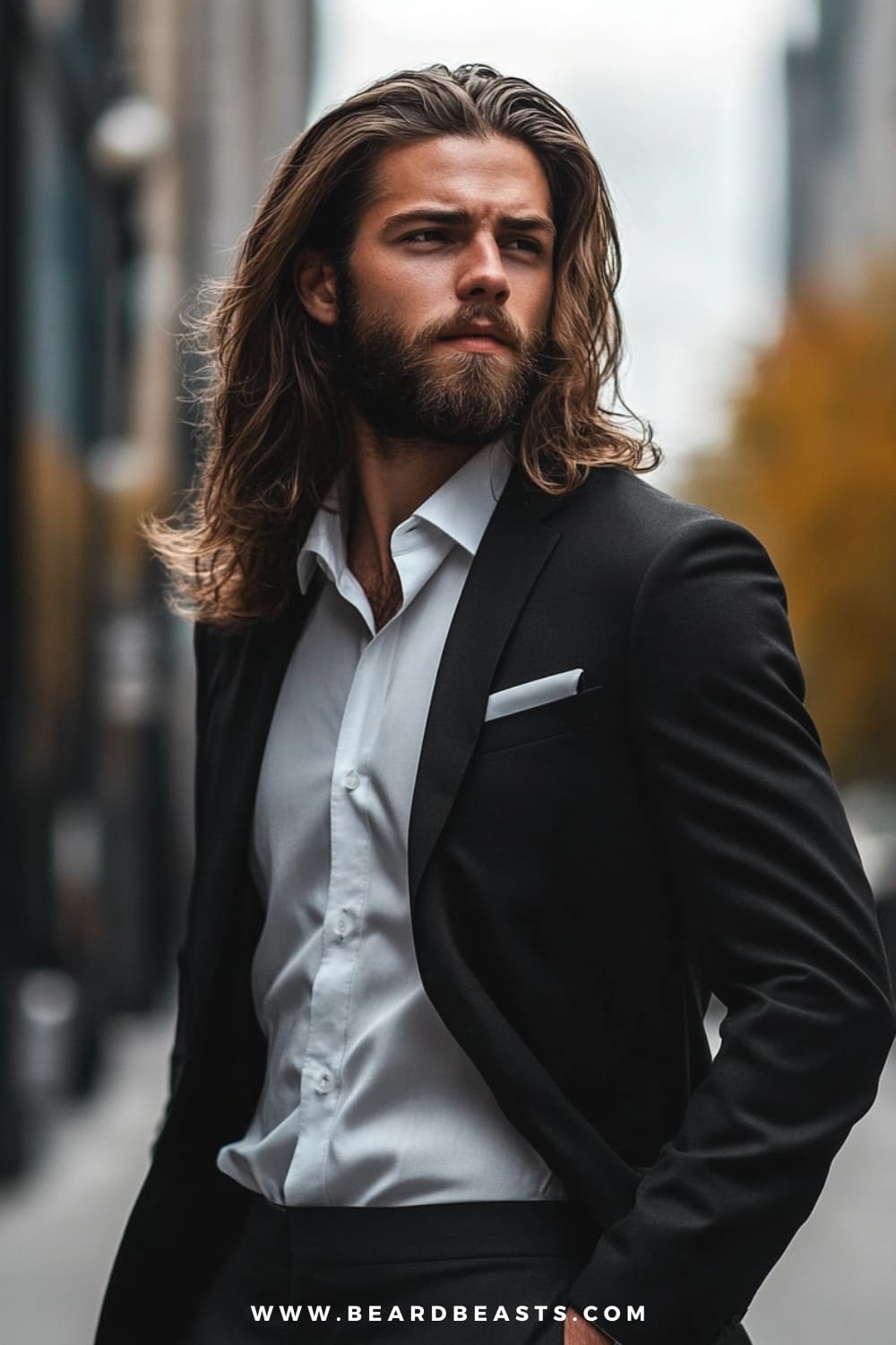 Man with long and flowing hair, styled naturally for a relaxed yet sophisticated look. The soft waves fall just past the shoulders, adding a touch of elegance and rugged charm. Paired with a tailored black suit and a white shirt, this hairstyle showcases a modern take on men's formal hairstyles, blending both casual and formal elements seamlessly. Ideal for men with longer hair looking to maintain their natural style in a formal setting.