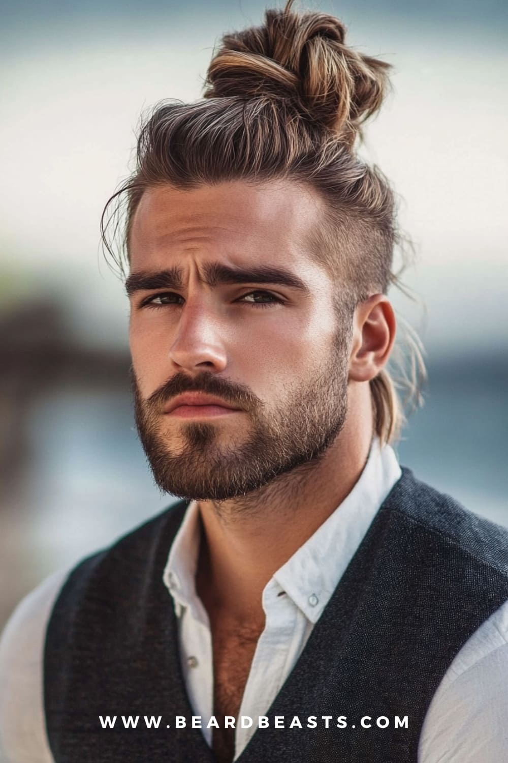 A man with a long top knot and undercut. The edgy undercut paired with the casual top knot creates a bold yet laid-back look, perfect for a modern beach-ready style.