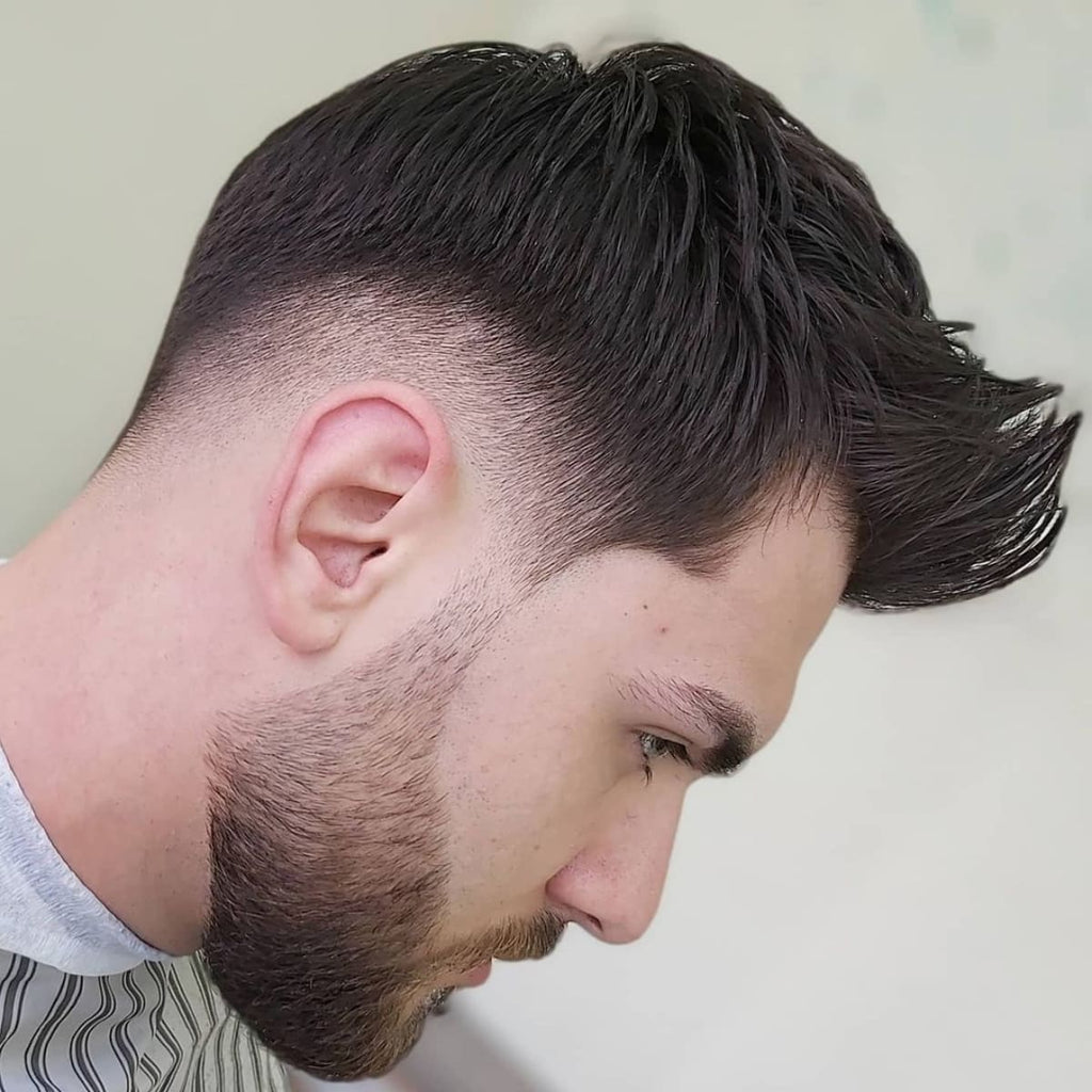 Side profile of a low drop fade quiff hairstyle with a smooth fade that curves down behind the ears and a textured, lifted top. This low drop fade quiff style gives a sleek, modern look, pairing a structured quiff with a well-groomed beard for added definition and style.