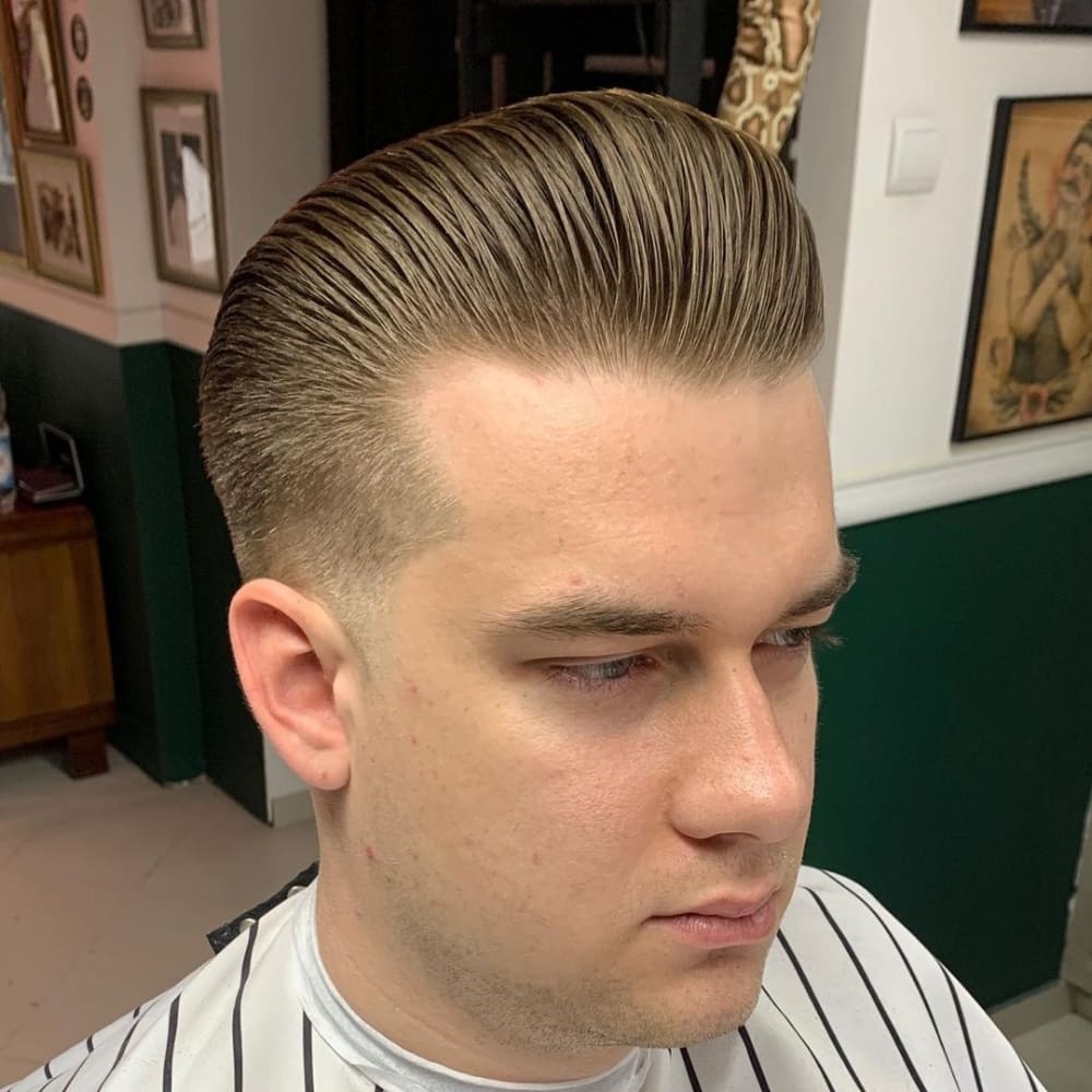 Man with a low fade pompadour haircut, featuring a sleek, voluminous top and cleanly tapered sides, showcasing a modern and stylish look ideal for 2024 trends.