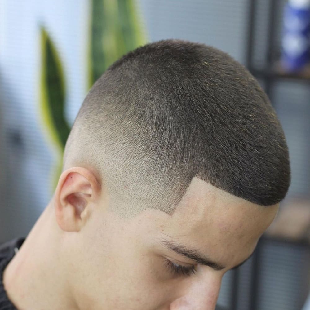 Man with a low skin fade haircut, featuring a sharp, clean fade that transitions smoothly from very short hair to skin, showcasing a modern and edgy look for 2024.