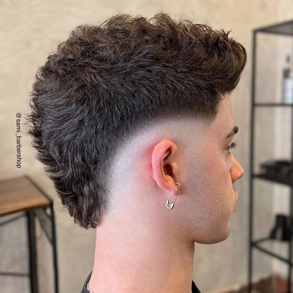 Man with a low skin fade fauxhawk haircut, featuring a bold and textured top with a sharp fade that transitions smoothly to the skin, showcasing a modern and edgy look for 2024.