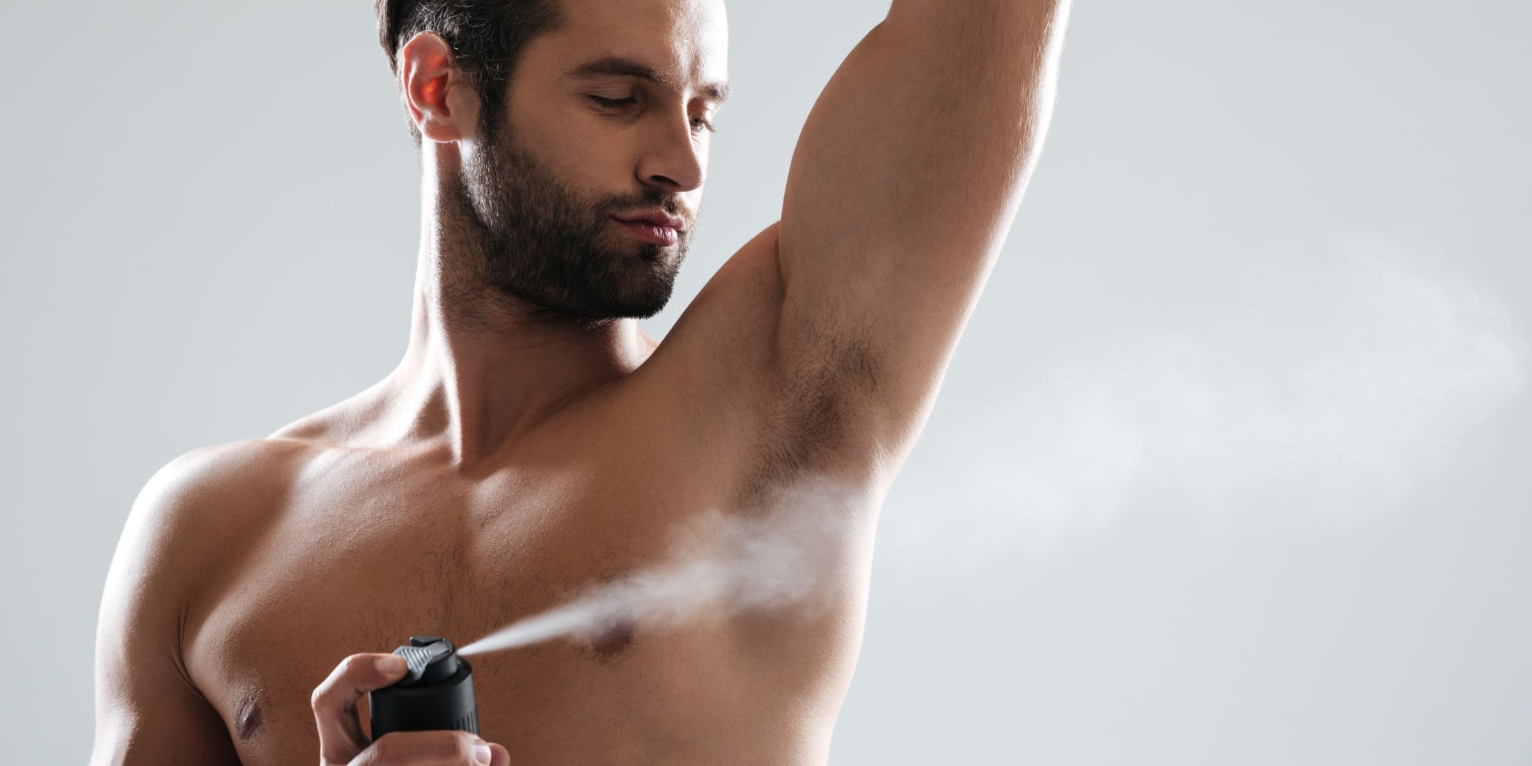 A man applying deodorant to stay fresh, demonstrating grooming tips on how to smell better as a man.