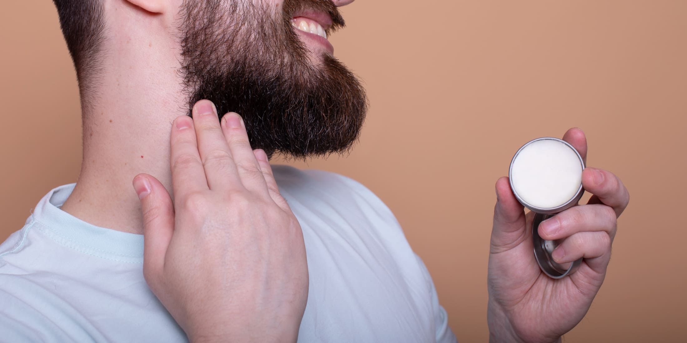 Man applying beard balm to his beard: Close-up of a bearded man using beard balm for styling and conditioning, highlighting the difference between beard oil and beard balm in beard grooming routines.