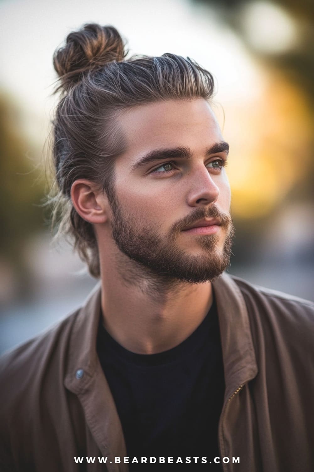 A man with a stylish man bun is featured in this image, showcasing a neatly tied bun with long hair pulled back from the face. This long hairstyle for men with thin hair works perfectly by gathering the hair into a bun, creating a fuller appearance while keeping the look clean and effortless. His subtle, natural waves add texture to the style, and the well-groomed beard complements the laid-back, yet sophisticated vibe. The man bun is ideal for those with long, thin hair, offering both practicality and style in one look, perfect for casual or polished settings.