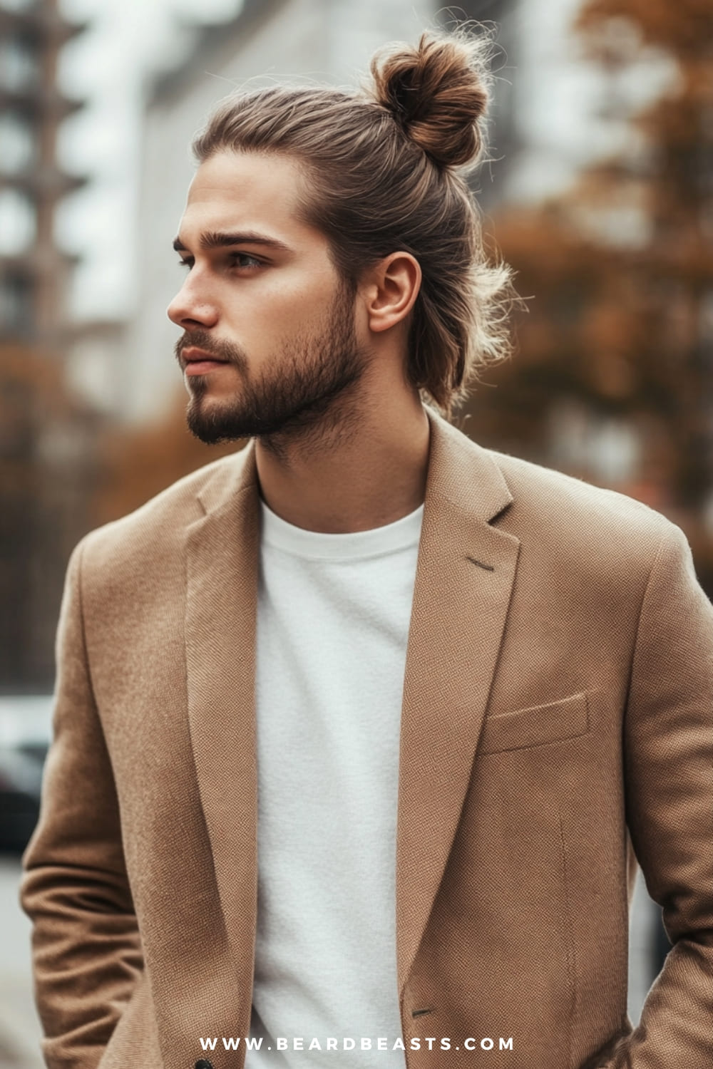 Man with a stylish man bun and well-groomed beard, dressed in a casual yet refined outfit. This look highlights one of the most popular men's hairstyles for long hair, blending a modern, effortless vibe with polished sophistication.