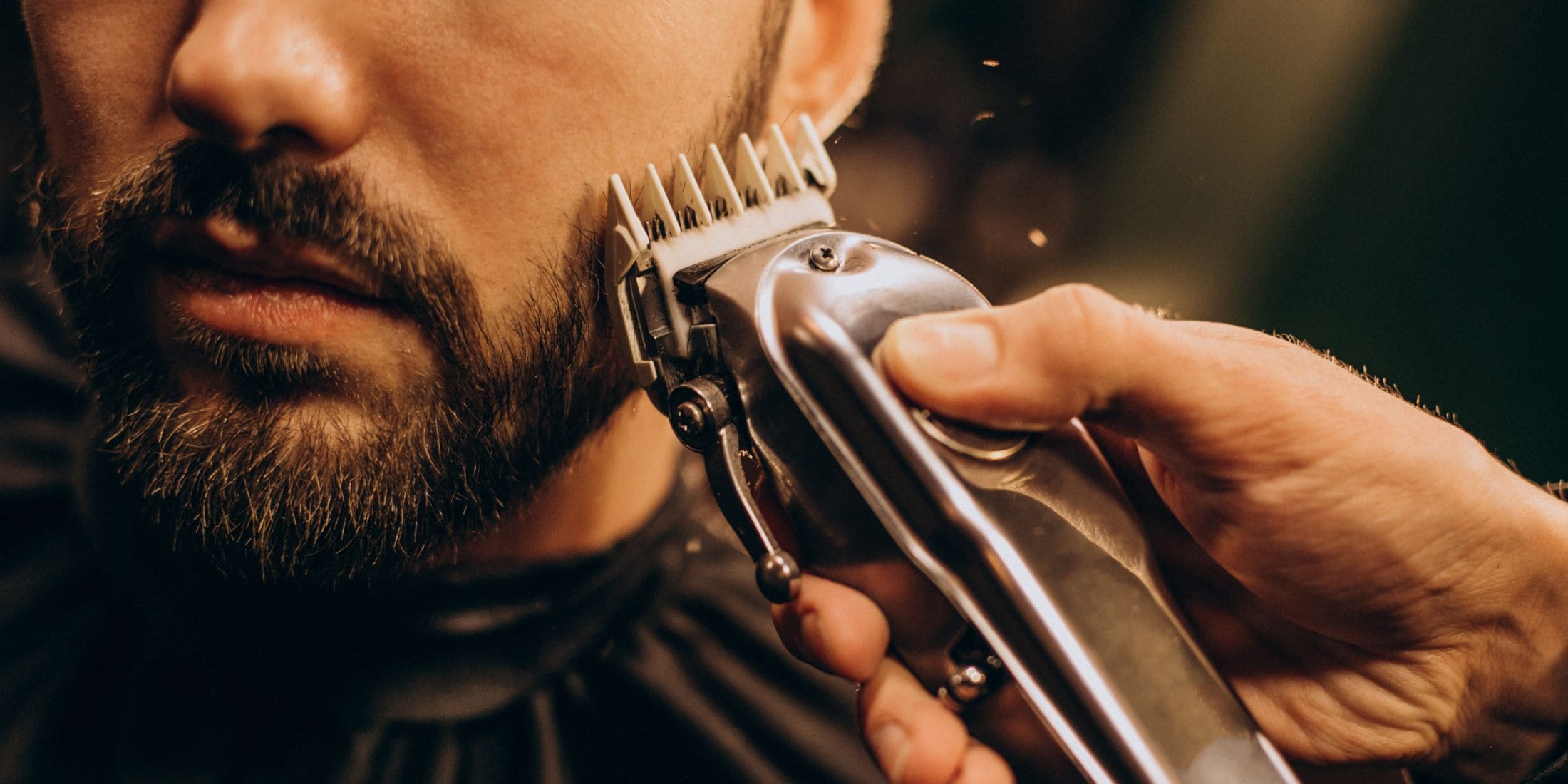 Close-up of a man receiving a beard trim using beard trimmer guards, showcasing precision grooming and effective use of a trimmer guard for a well-maintained beard.