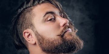 Close-up of a man with a stylish full beard and mustache, showcasing one of the best beard styles for square faces, with a sharp jawline and modern hairstyle.