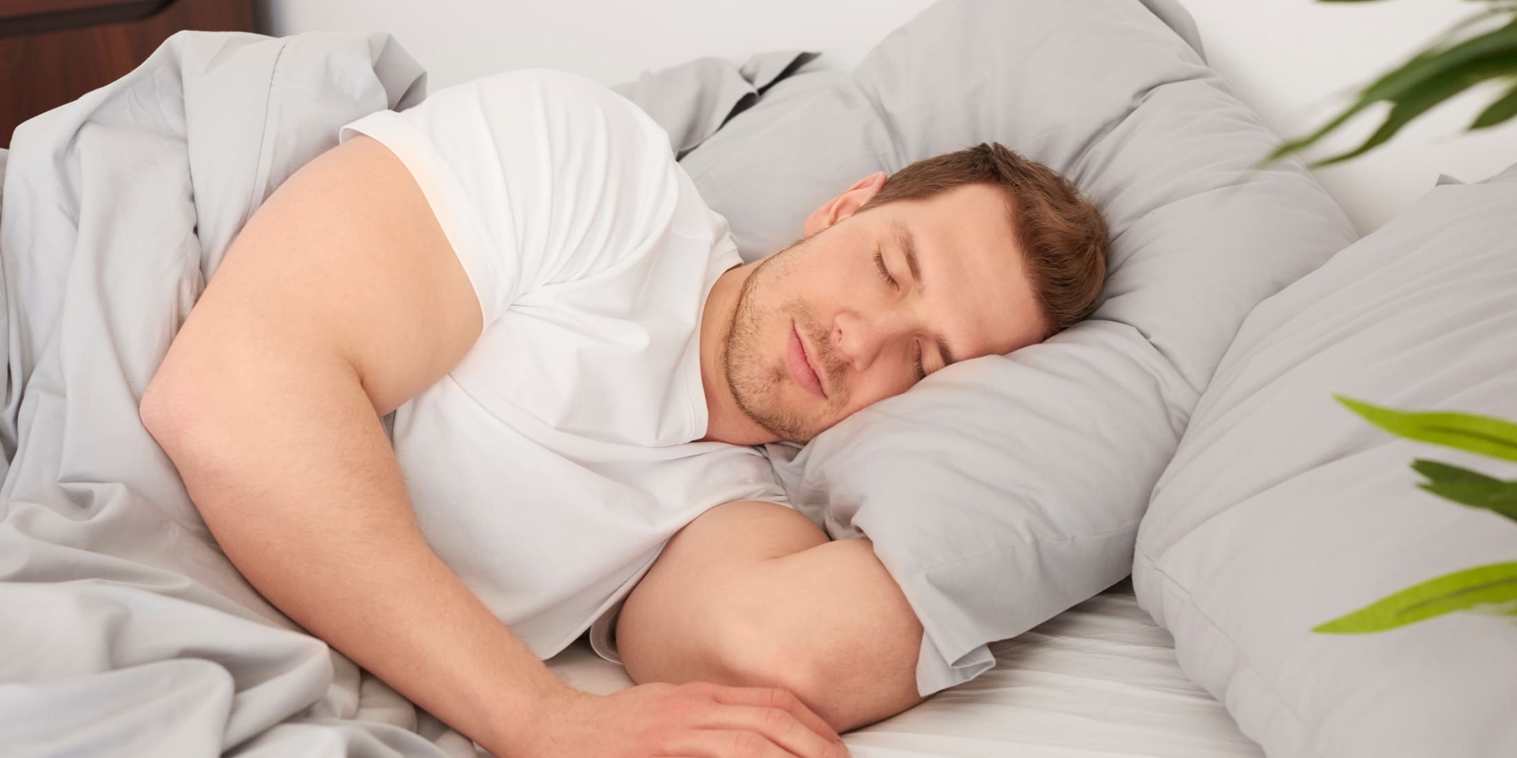 A man peacefully sleeps on his side, highlighting the importance of quality rest as part of self-care for men. His relaxed expression and cozy bedding emphasize the role of adequate sleep in maintaining energy, reducing stress, and promoting overall well-being.