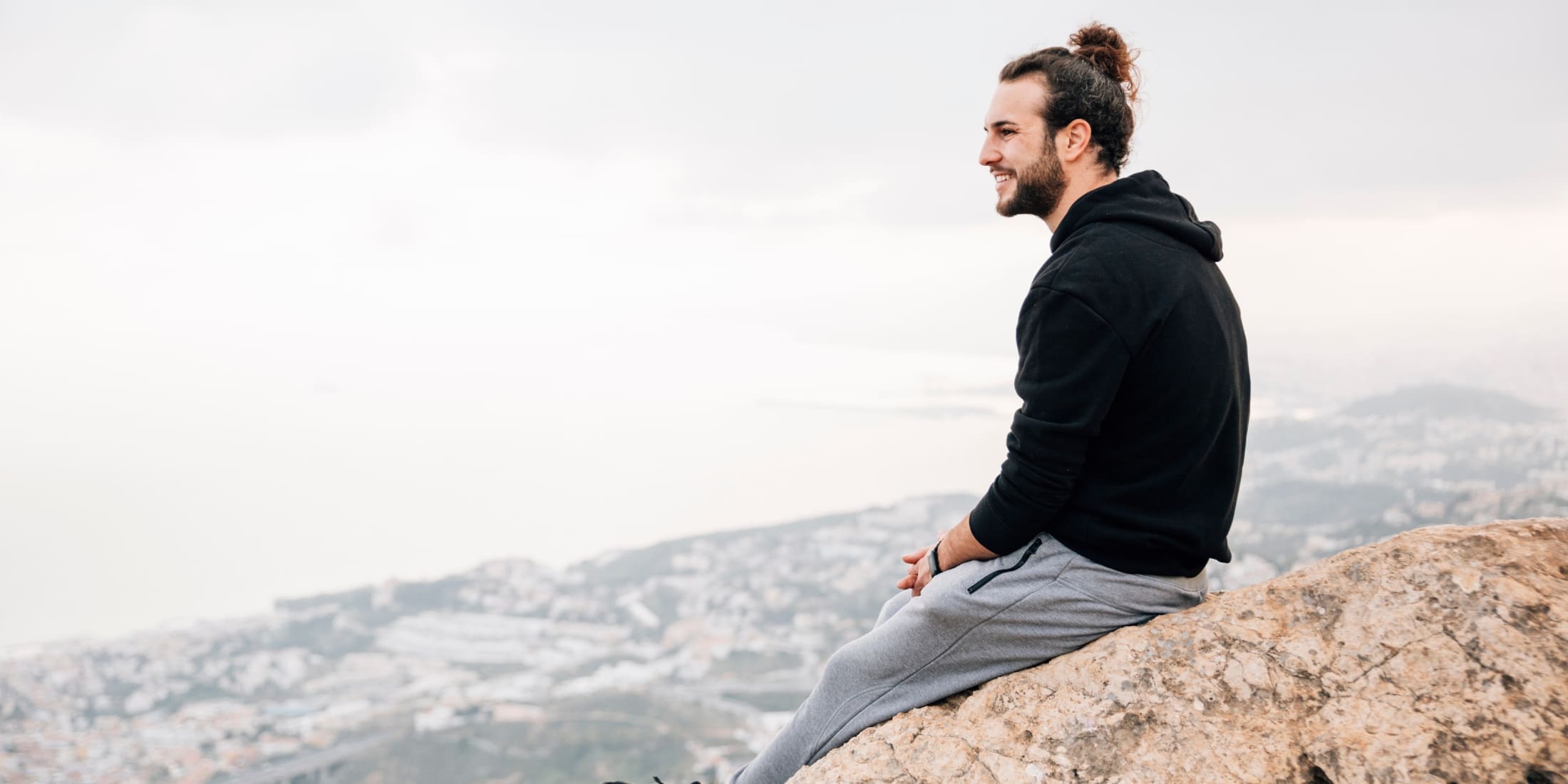 A man practicing mindfulness for men on a mountaintop, taking a peaceful moment to be present and reflect, overlooking a scenic landscape, promoting mental clarity and stress reduction.