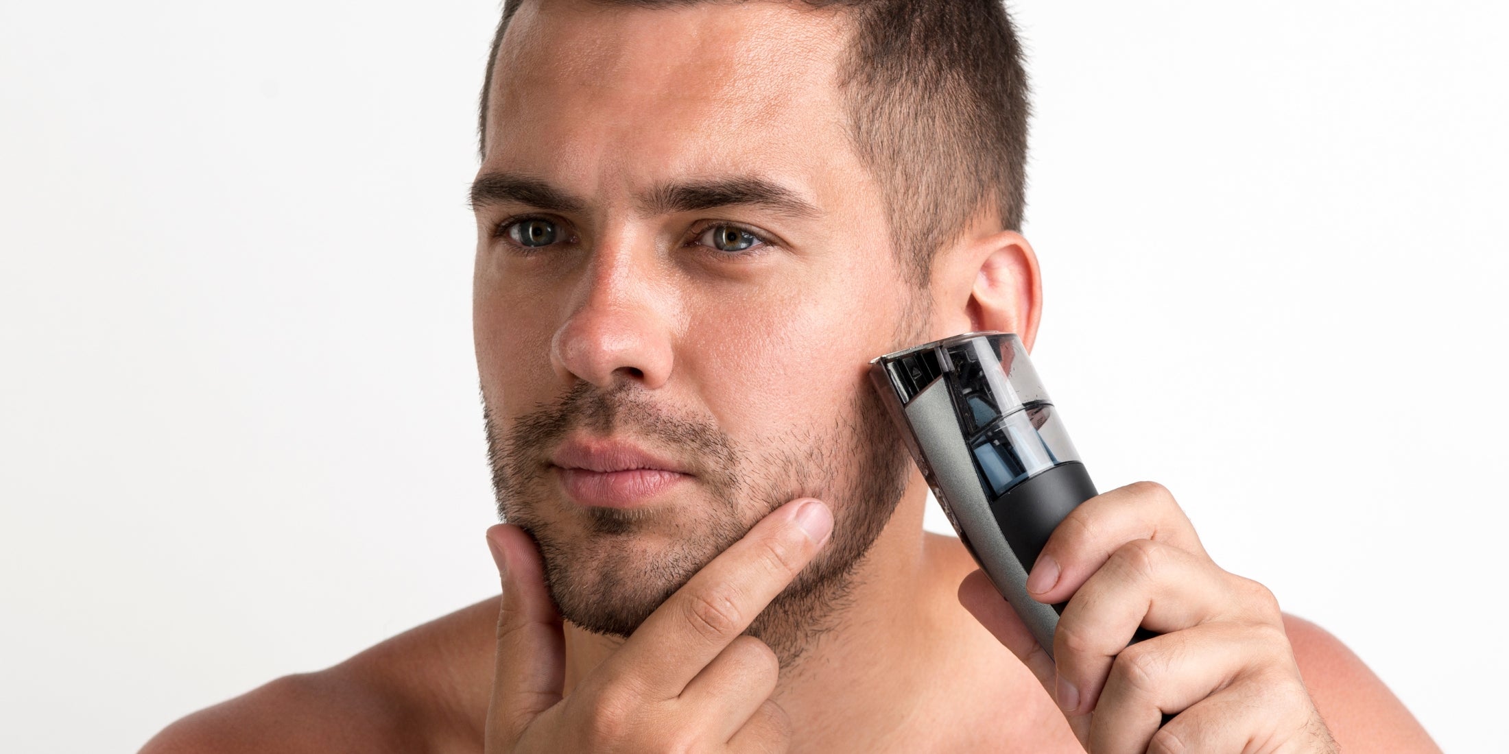 A man is using a trimmer to carefully maintain his 3mm beard. He has a focused expression as he ensures an even trim along his jawline. The image highlights the precision and attention to detail required to keep a 3mm stubble looking neat and well-groomed.