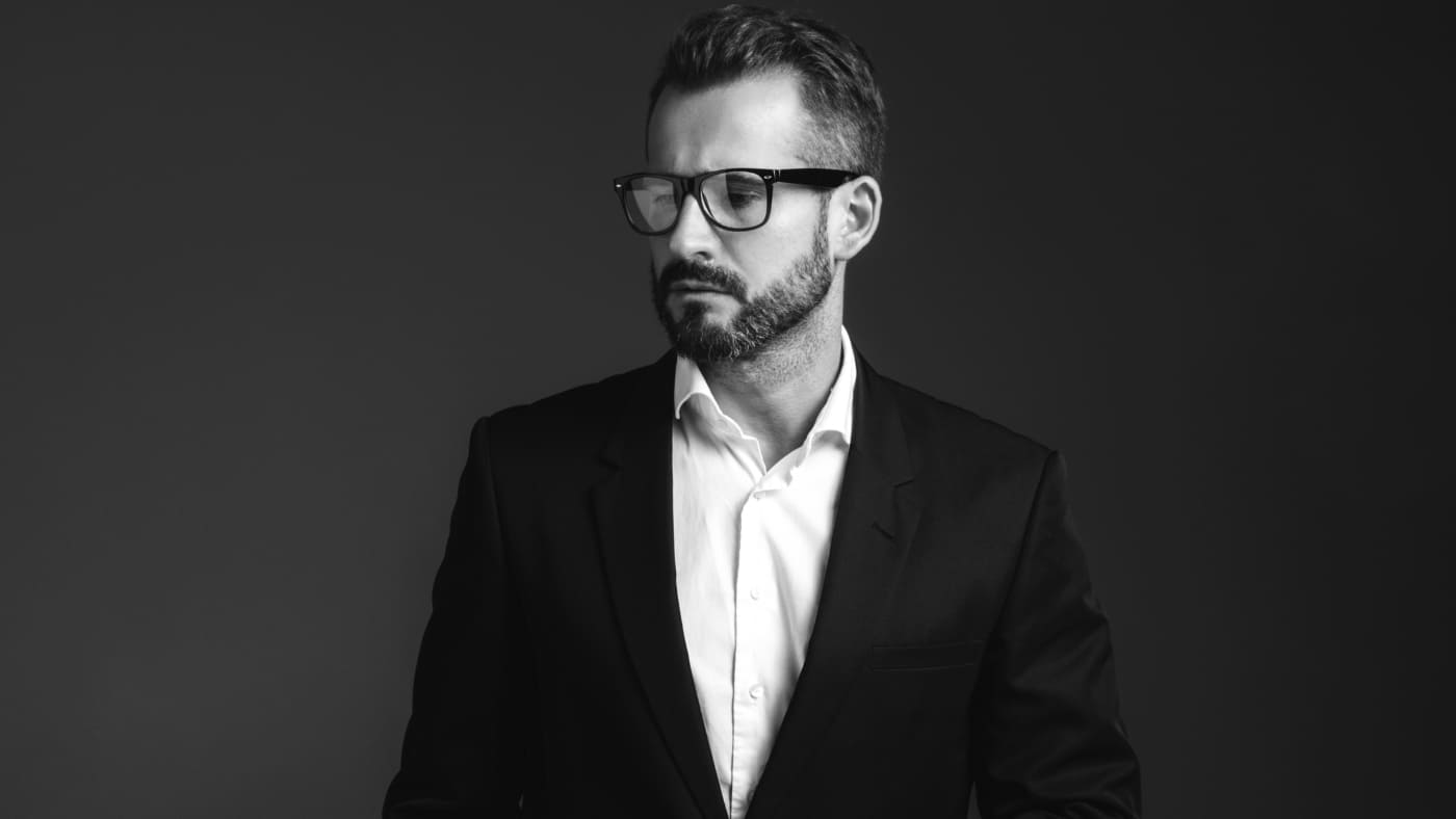 Man in suit sporting a stylish one month beard and glasses