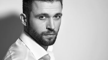 Close-up of a man with a well-groomed one month beard in a white shirt