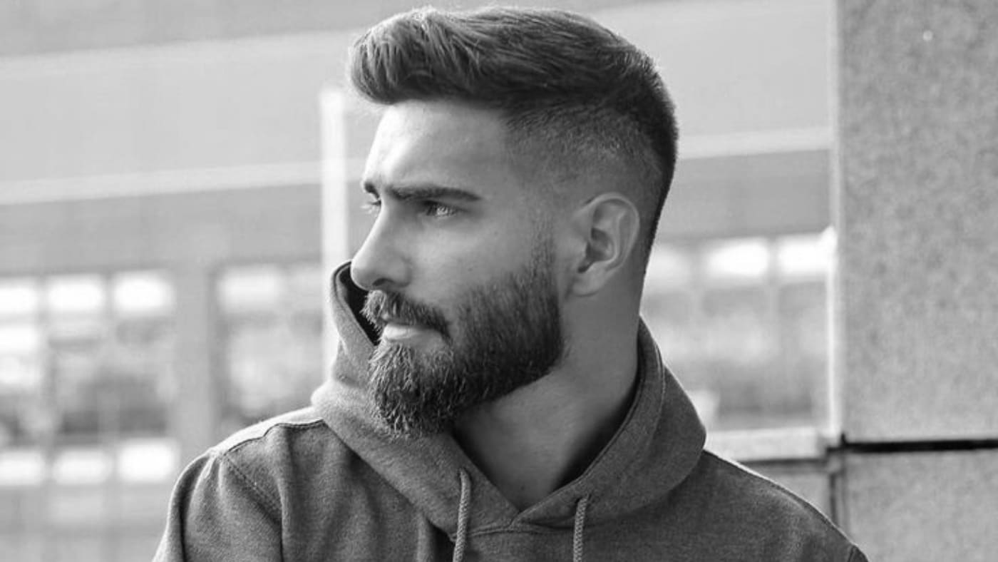 Modern man in a casual hoodie showcasing a sharp 20 mm full beard, profile view