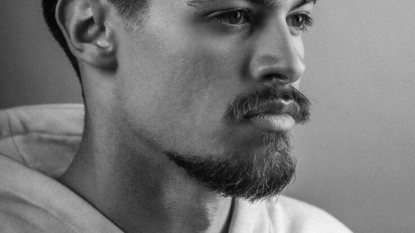 Close-up of a thoughtful man with a meticulously groomed 20 mm goatee and mustache.