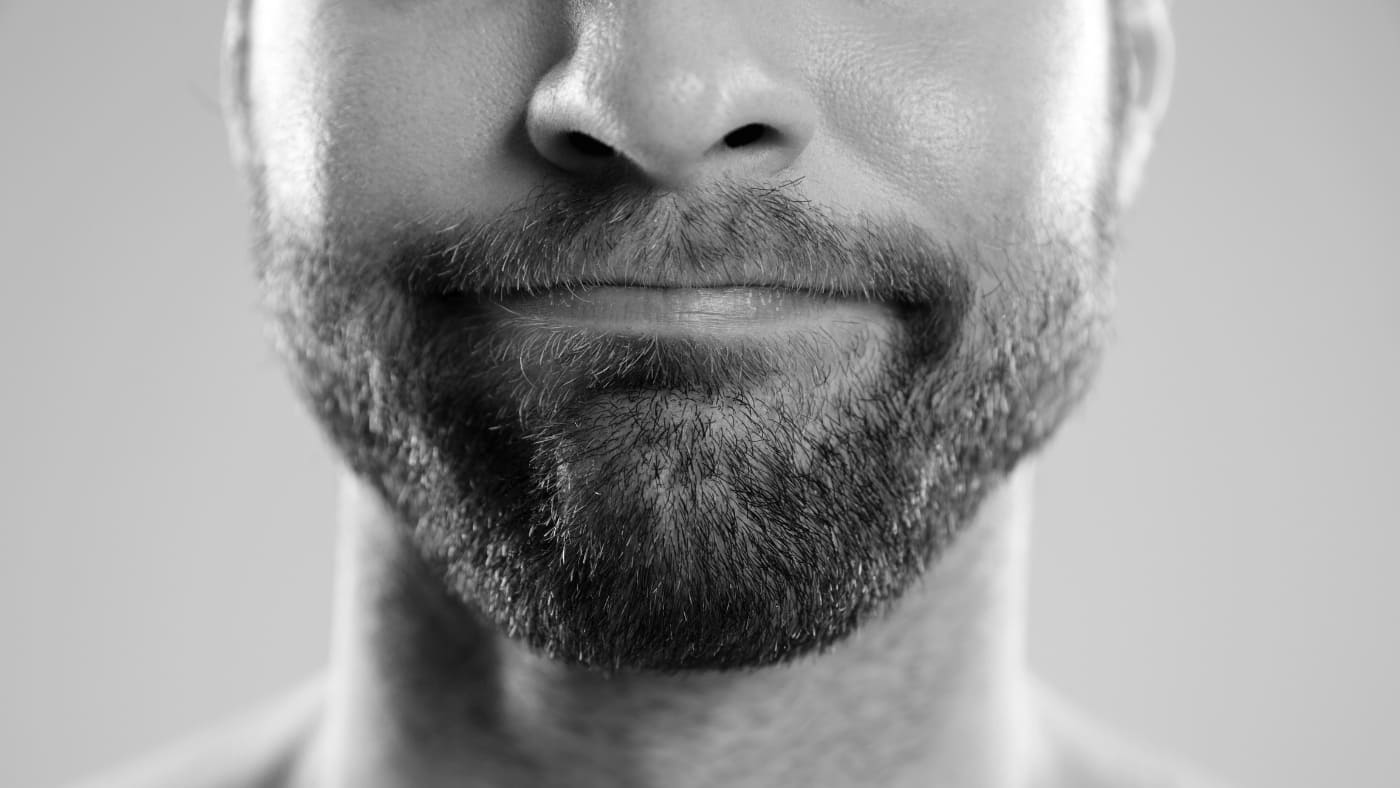 Close-up of a content man with a meticulously groomed 6-week beard, black and white image