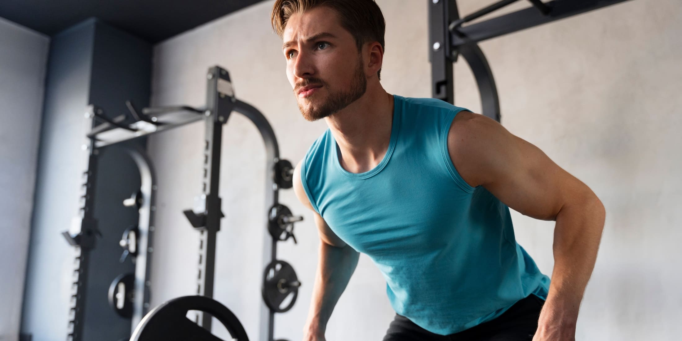 A focused man in a gym working out in the morning, performing strength training exercises.