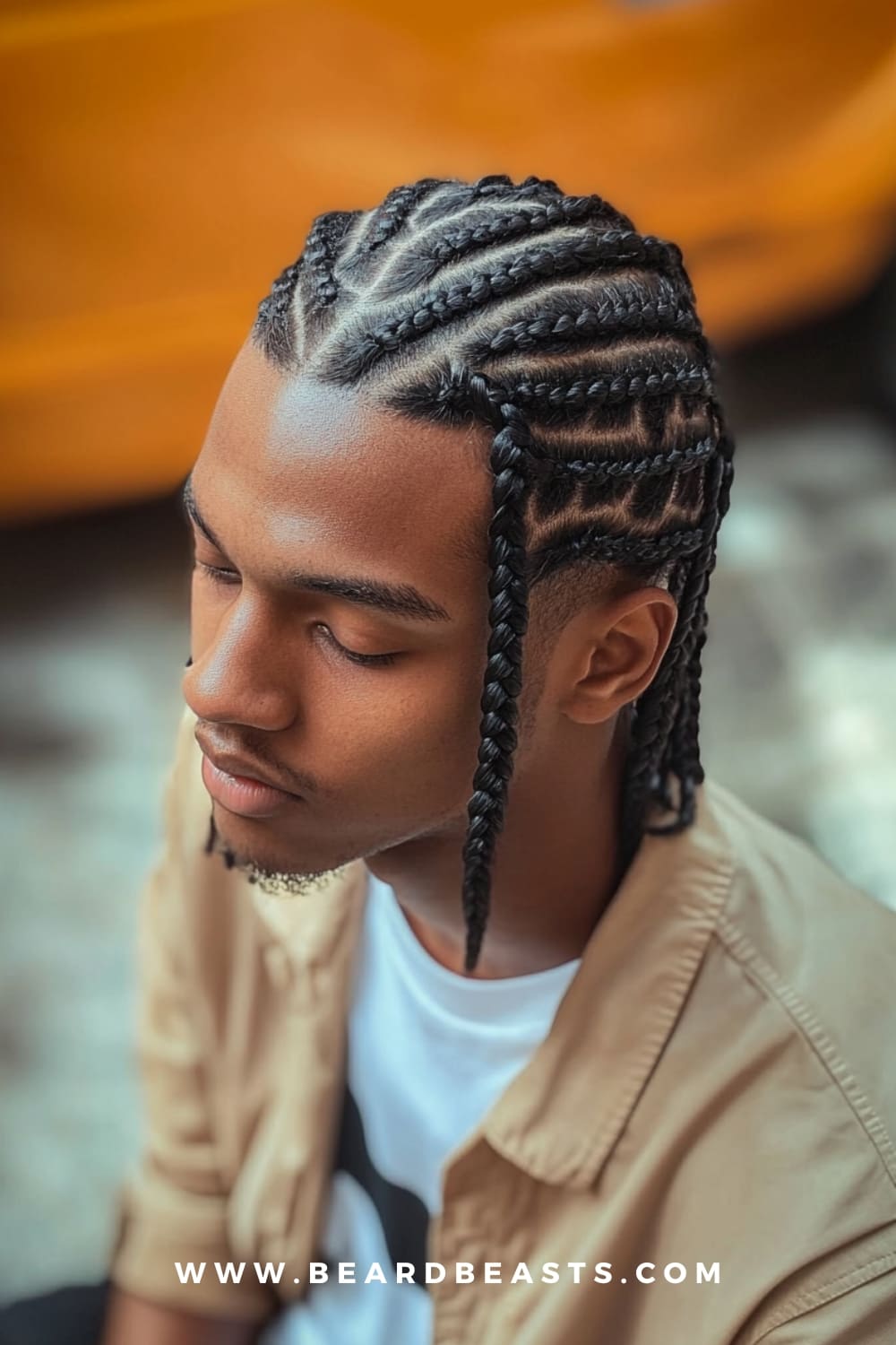 Man with neatly styled braids, showcasing a clean and intricate look. Braids are a great option among low maintenance haircuts for men, offering a stylish and long-lasting hairstyle that requires minimal daily upkeep.