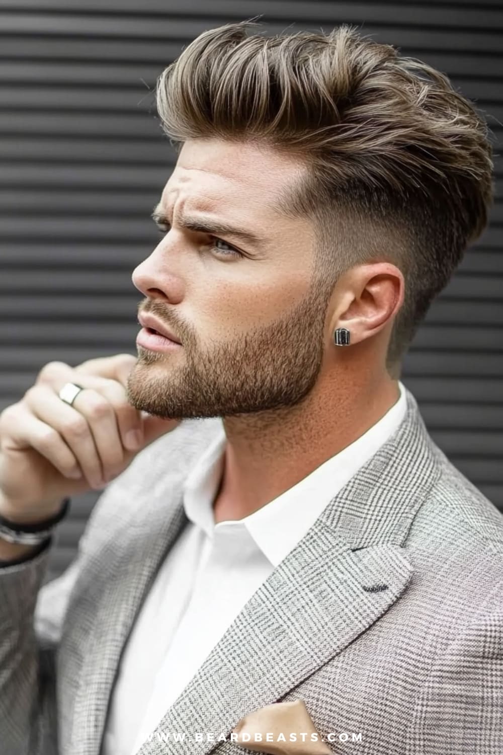 Man featuring a stylish brushed-up hairstyle, with voluminous hair on top styled upward for a bold, clean look. The sides are neatly faded, providing a modern contrast to the lifted top. Complemented by a well-groomed beard and paired with a light plaid suit and white shirt, this look is a standout among men's formal hairstyles. Ideal for formal occasions where a sharp, confident appearance is essential, this brushed-up hairstyle exemplifies modern elegance in men's formal hairstyles.