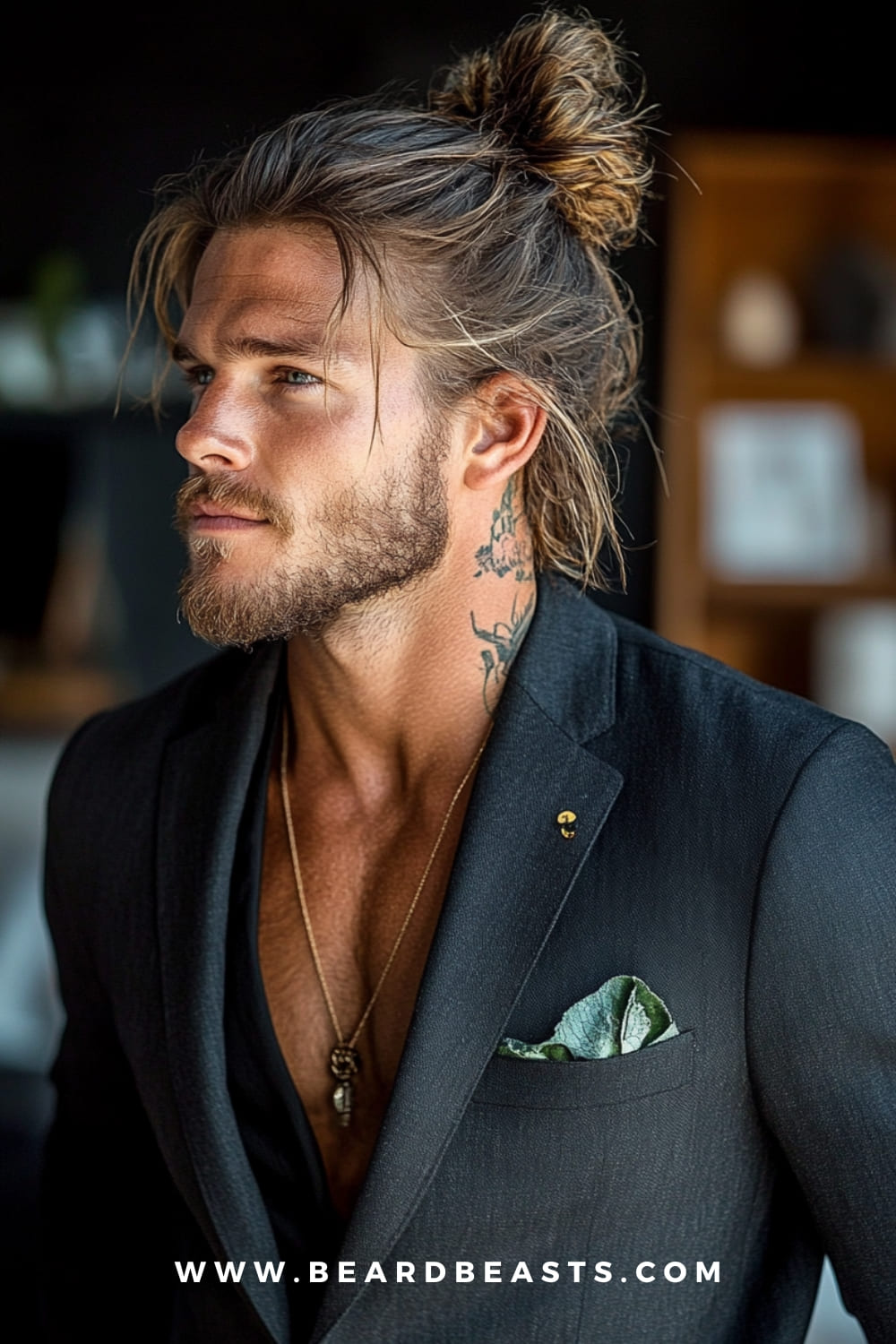 A man sporting a trendy man bun, featuring long, textured hair tied back with loose strands framing the face. Paired with a beard and tattoos, this look exemplifies stylish haircuts for men, blending a rugged yet polished vibe.